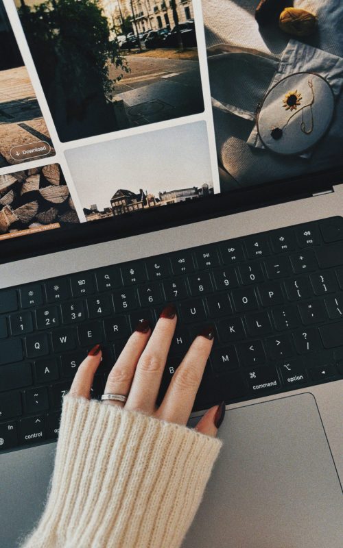 Close-up of a hand with painted nails on a laptop keyboard, cozy autumn vibe.